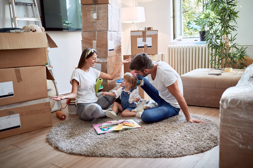 Youngfamilyofthreeplayingonacarpetinnew How Do You Make A Move Easier For Kids